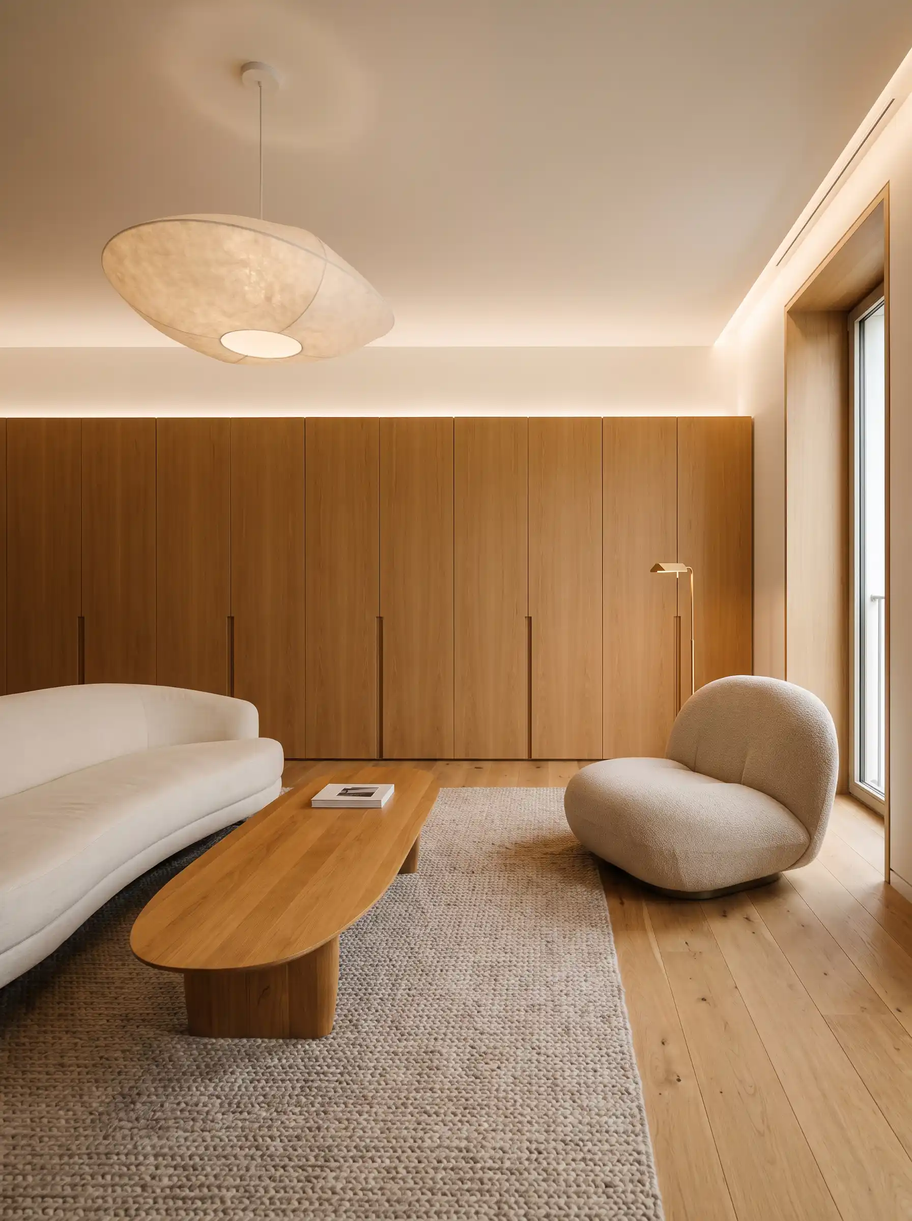 Ultra minimalist Scandinavian living room with curved white sofa oak cabinetry and cloud pendant light